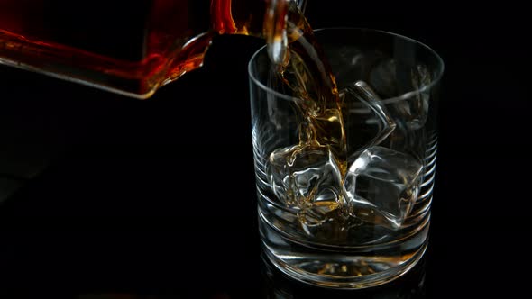 Super Slow Motion Shot of Pouring Whiskey From Bottle in Glass with Ice Cubes with Camera Movement