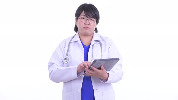 Happy Overweight Asian Woman Doctor Talking While Using Digital Tablet