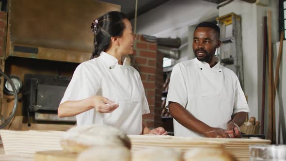 Animation of happy diverse female and male bakers preparing sourdough and talking