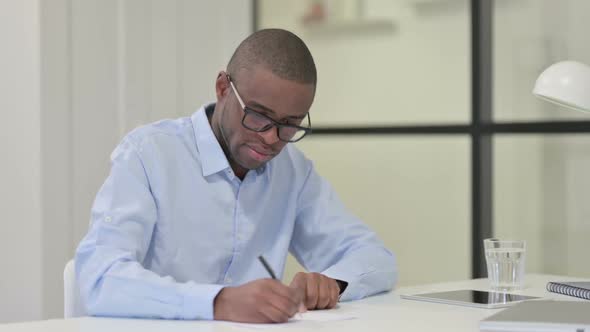 African Man Writing on Paper at Work