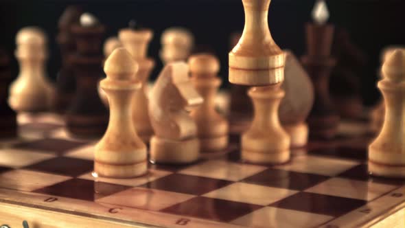 A Super Slow Motion Chess Figure Falls on a Board with Splashes of Water
