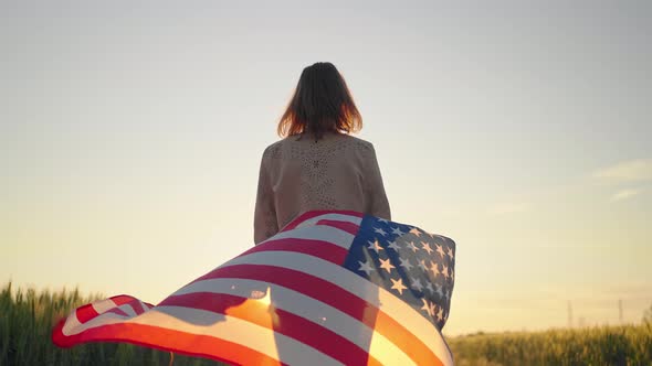 Slow Motion Rear View of Young Beautiful Sexy American Woman Holding a American Flag Walking Wheat