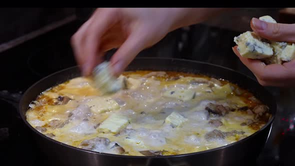 Chef's Hand Adds Blue Cheese with Mould to Boiling Pan with Delicious Food