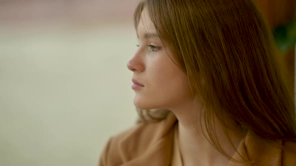 young Lonely sad woman looking away out of coffee shop window to city street