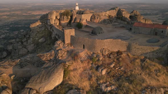 Monsanto castle and surrounding landscape at sunrise, Portugal. Aerial backward ascendent