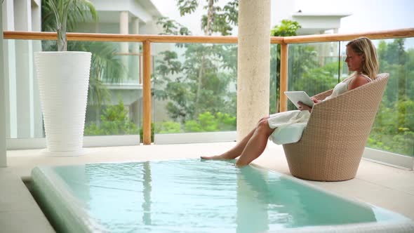 Woman uses digital tablet by pool at tropical resort