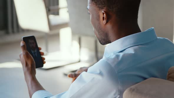 Young businessman making video conference with boss on smartphone