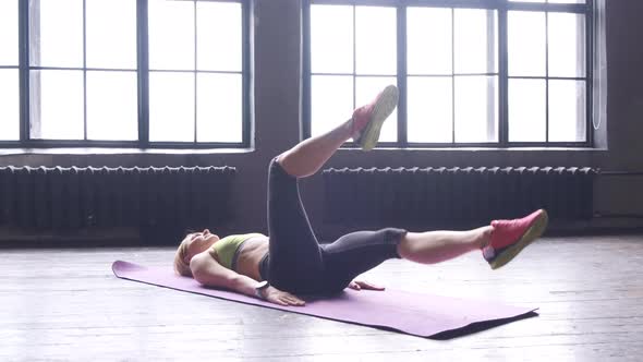 A Young Blonde Woman Is Doing A Leg Exercise Doing Sports In A Fitness Studio With Large Windows