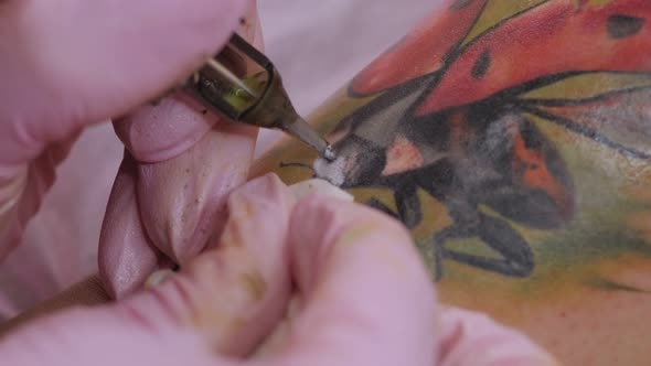 Needle Tattoo Machines Inject a Black Ink Into the Skin of a Woman