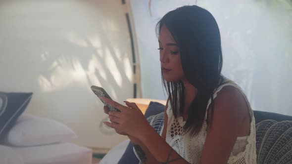 Portrait of a Pretty Asian Woman Using Her Mobile Phone Inside the Tent House