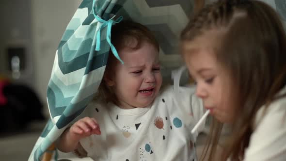 Little Baby Girl in Cute Clothes Crying While Playing with Her Preschool Sister 56Years at Home in