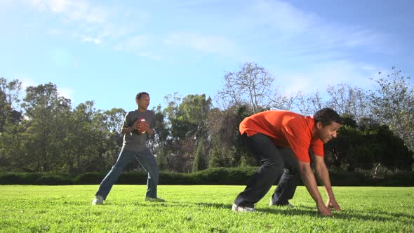 A father teaching his sons how to play American football.