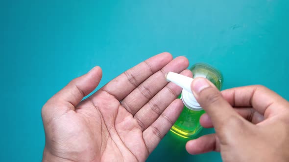 Close Up of Young Man Hand Using Sanitizer Gel on Green Background 