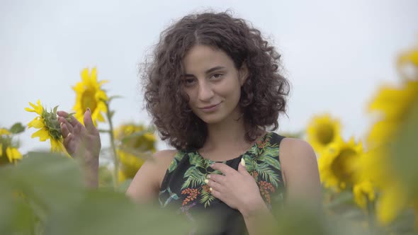 Pretty Curly Playful Smiling Girl Standing on the Sunflower Field