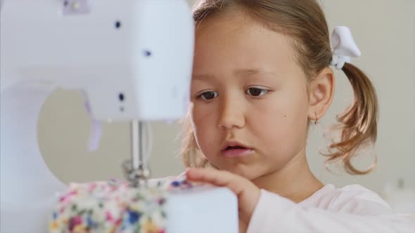 Close-up of a Little Girl Who Is Making Stiches on Sewing Machine. Portrait.