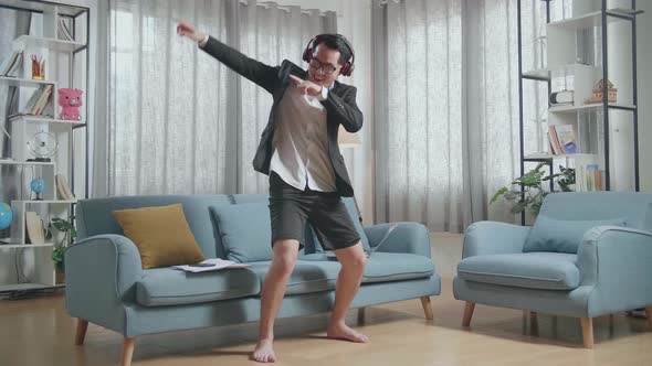 Full View Of Asian Businessman In Jacket And Shorts Listening To Music With Headphones And Dancing