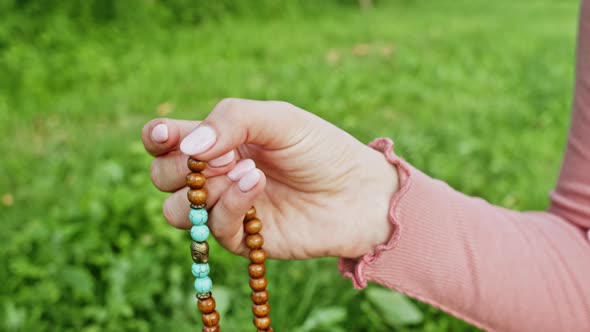 Woman Lit Hand Close Up Counts Rosary - Malas Strands of Gemstones Beads Used for Keeping Count alt