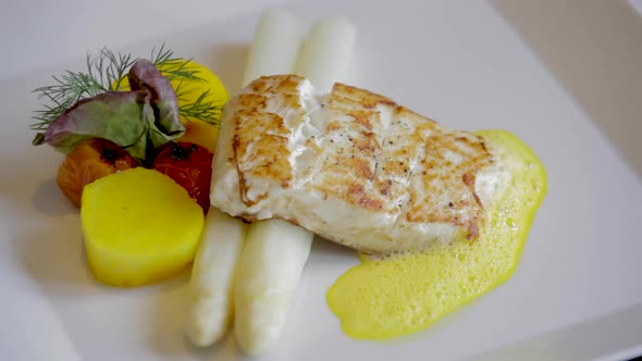 Restaurant Made Fish With Potato Asparagus and Sauce Hollandaise on Rotating Plate