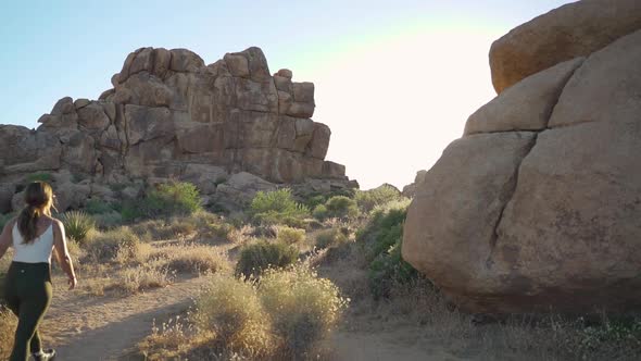 Girl hiking in the California national desert near Joshua tree, sun flaring into lens, slow motion