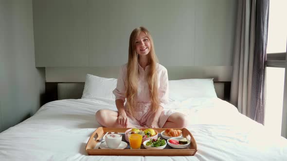 Breakfast in Bed  Happy Woman Sitting on Bed in Hotel Drinking Coffee