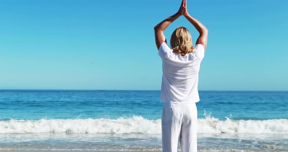 Rear view of man performing yoga at beach