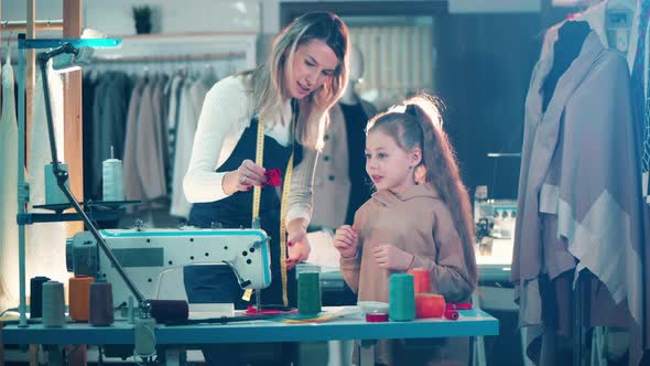 A Seamstress is Teaching a Girl to Work with Fabric