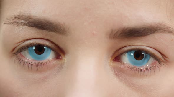 Closeup of a Browneyed Young Woman Wearing the Blue Decorative Lenses Opening Eyes and Closing