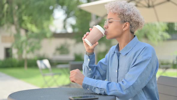 Young African Woman with Coffee Having Toothache in Outdoor Cafe