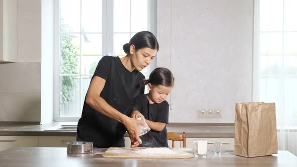 Mom and Little Daughter are Cooking Something From Flour in the Kitchen