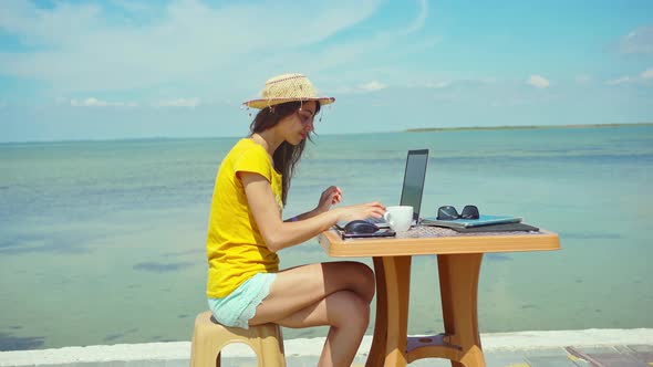 Portrait Freelancer Woman in Hat Holding Smartphone Working on Laptop Computer By Seashore