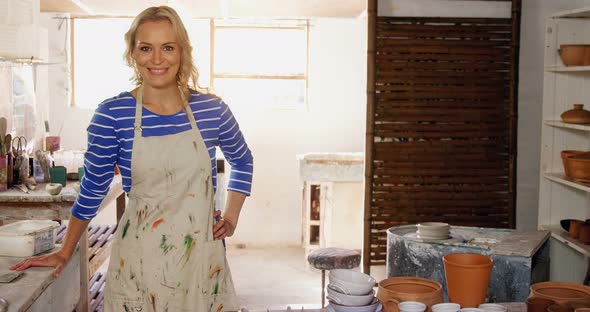 Beautiful female potter standing in pottery shop