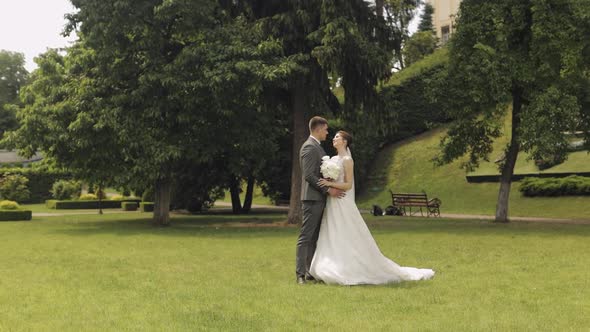 Newlyweds Caucasian Groom with Bride Walking Embracing Hugs in Park Wedding Couple