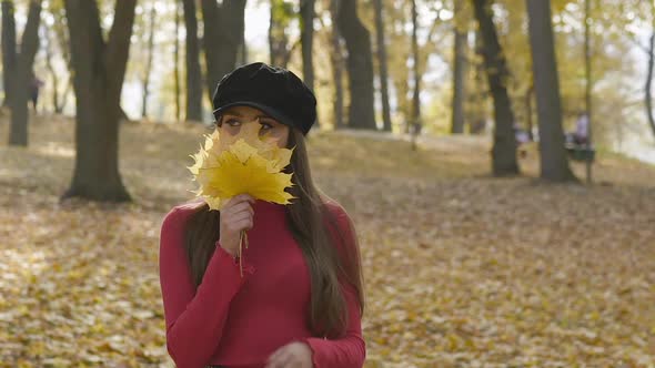 Happy Young Girl Holds a Maple Leaves Bouquet Throwing It Up and Laughing