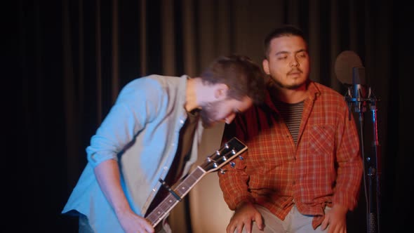 Recording a Song in the Recording Studio - Two Men Sitting Down and Preparing for the Record