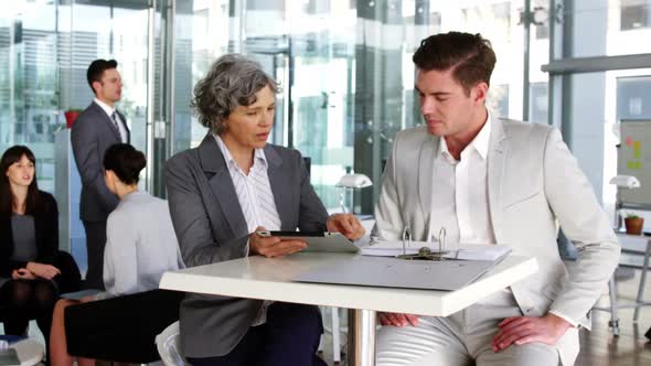 Businesswoman discussing over digital tablet with colleague