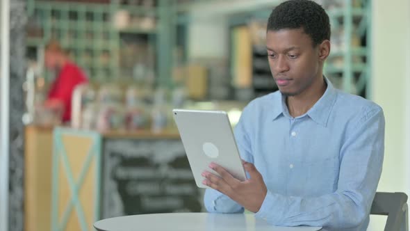 Professional Young African Man Using Tablet in Cafe