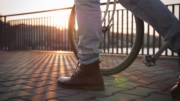 Close Up Shot of Young Stylish Hipster Walking with His Bicycle on Sea Port Background During Sunset