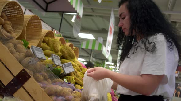 Attractive Young Woman Chooses Potatoes Shopping in the Supermarket Buys Healthy Food Potatoes in