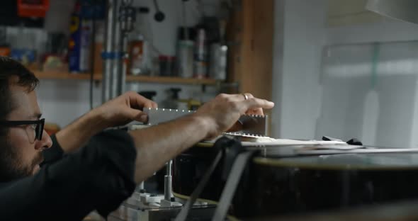 Luthier Adjusts the Fretboard Angle in the Electric Guitar Mounted on the Jig Repairing the Musical