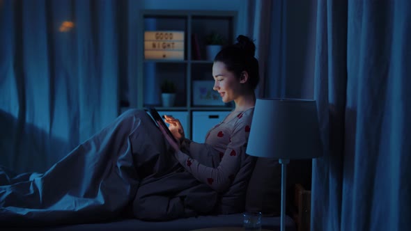 Teenage Girl with Tablet Pc in Bed at Night