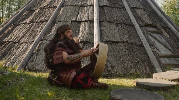 Obese Man Repairs Shamanic Drum Sitting Near Old Ail