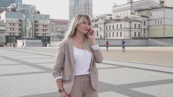 Business woman talking on the phone in the center of a big city.