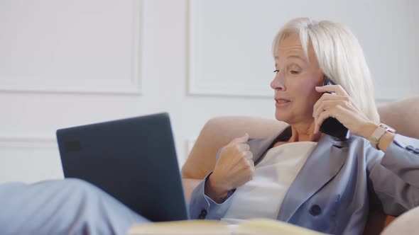 Female Office Worker Using Phone and Laptop