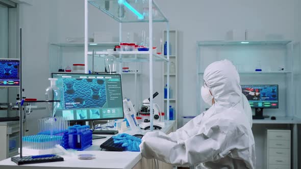 Chemist Typing on Pc and Coworker Analysing Microscope Slides alt