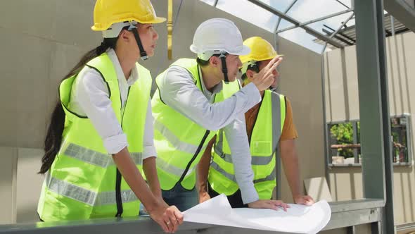 Asian colleague workers people wearing protective safety helmet and glasses onsite of architecture.