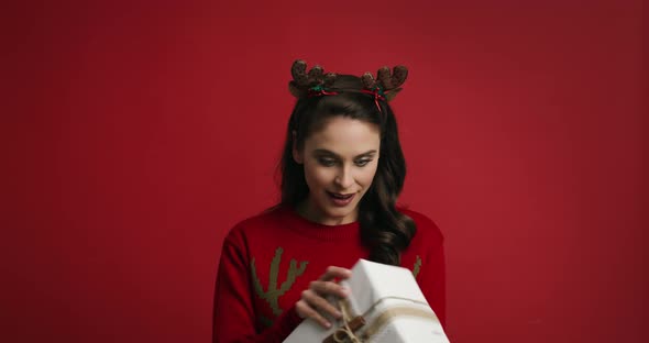 Woman with Christmas present on red background