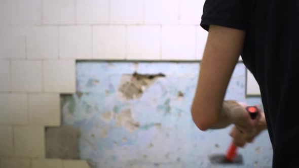 Man Breaking Tiles in the Bathroom with Hammer