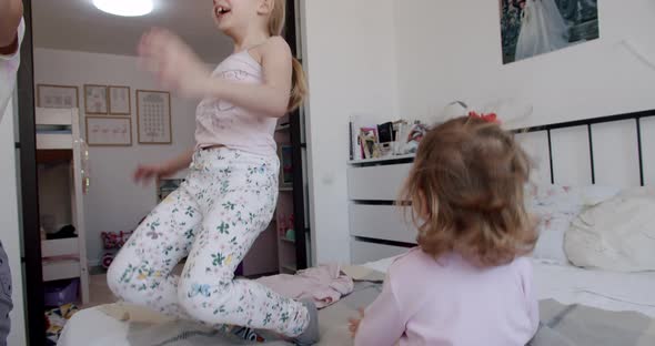 Two Little Girls are Playing at Home Jumping for Joy and Smiling Nicely