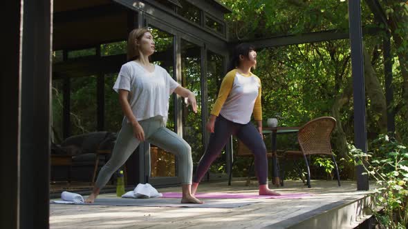 Asian mother and daughter practicing yoga outdoors in garden