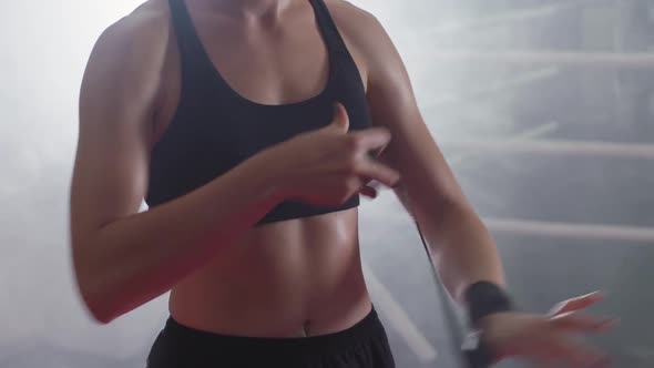 Female Fighter Wraps Her Hands with Boxing Bandages, Kickboxing Training Day in a Gym, the Girl Is